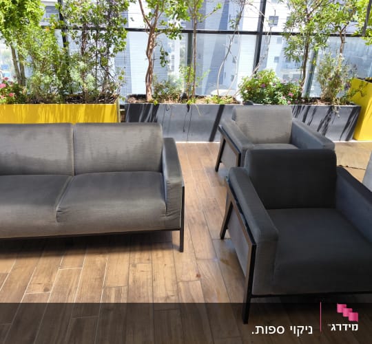 ספות אפורות על רצפת עץ עם צמחייה ברקע